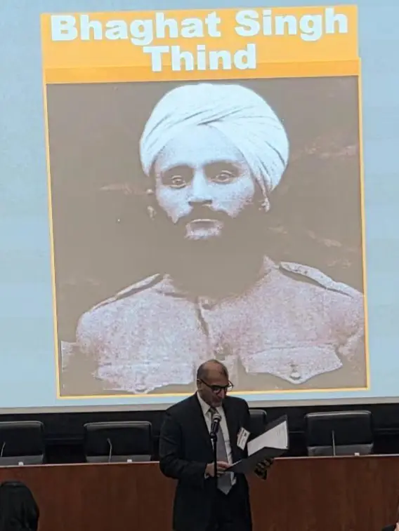 Vishal Chander reenacts Bhagat Singh Thind’s Supreme Court case in front of projected image of Thind in uniform