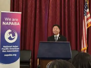 Congressman Ted Lieu speaking at a podium beside a NAPABA banner and U.S. flag during the CAPAC reception at NAPABA Lobby Day 2025